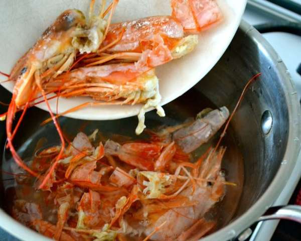 Займемся приготовлением рыбного отвара (или бульона...), который будем использовать для приготовления ризотто. В отдельную кастрюльку налить 500 мл воды, положить панцири, головы и все, что у нас осталось от креветок. Проварить минимум 30 минут. Процедить полученный отвар через сито. Поддерживать горячим.   