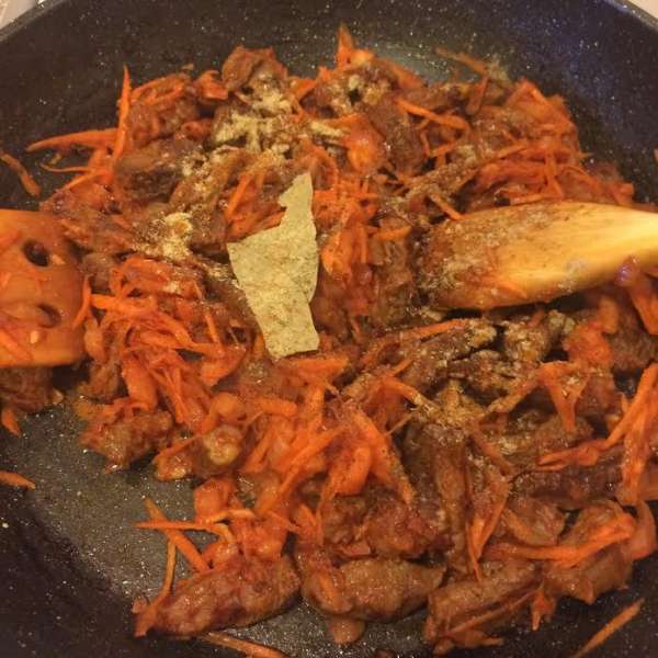 Морковь натереть на крупной терке, помидор очистить и нарезать. К мясу добавить томатную пасту, перемешать. Затем добавить морковь, помидор, специи, лавровый лист, 1/2 стакана воды, накрыть крышкой и тушить до готовности мяса.