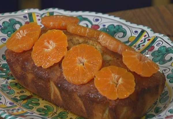 Оставшиеся мандарины почистить, нарезать поперек кружками и выложить на кекс. 