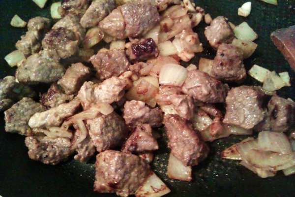 Перекладываем мясо с луком и чесноком из маринада на разогретую сковородку, отжимая маринад. Сначала на сковороде появится сок, когда он выкипит, подливаем немного подсолнечного масла. Обжариваем 10 мин. на сильном огне. Разогреваем духовку до 200 гр.