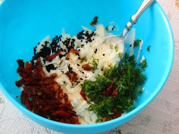 Сыры можно подобрать по собственному вкусу: твердый и жирный + мягкий и легкий, чтобы они при смешивании образовывали вязкую массу, из которой удобно лепить. Разминаем их в мисочке вилкой. Добавляем измельченные помидоры, укроп, орехи. Я указала в ингредиентах черный кунжут, но я добавляла чернушку, ее нет в списке, примерно 1 чайную ложку. Можно добавить обычный кунжут, мак, чеснок.