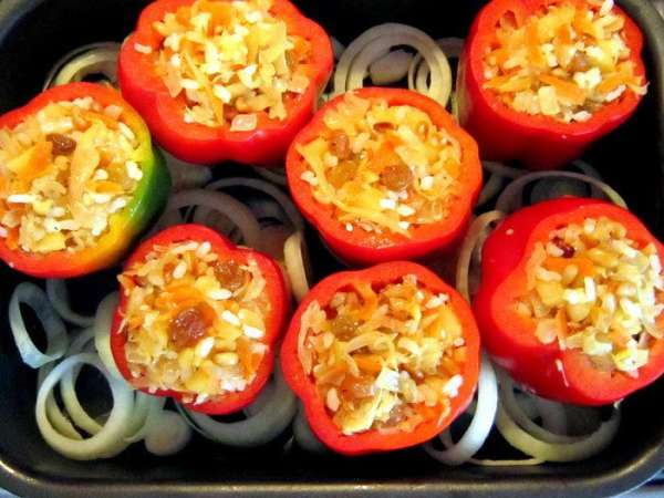 Аккуратно наполнить перчики смесью. Оставшийся лук порезать кольцами.
Противень смазать растительным маслом, положить кольца лука. Сверху выложить перцы и влить бульон (у меня куриный).