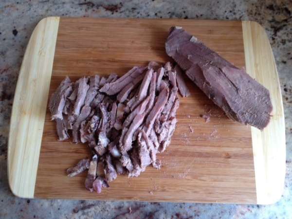  Нарезать тонкими кусочками отваренный и очищенный язык. 