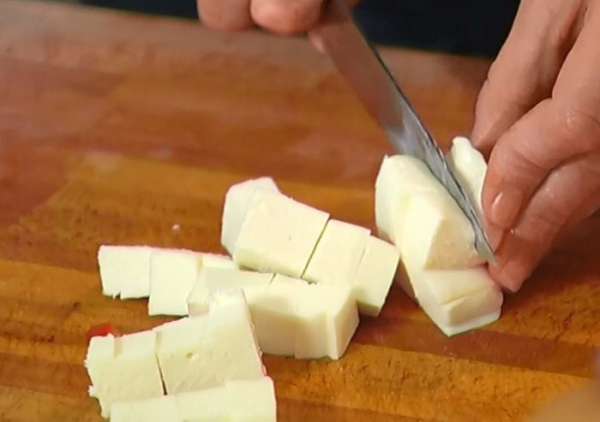Моцареллу нарезать кубиками и выложить в сковороду к помидорам.