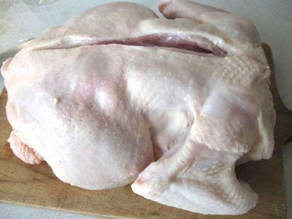 Положить курицу на доску грудкой вниз, надрезать по хребту.  
