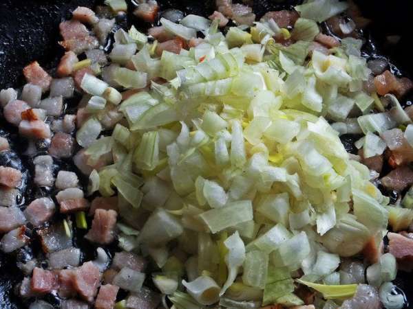 Высыпать к мясу в сковороду много лука.