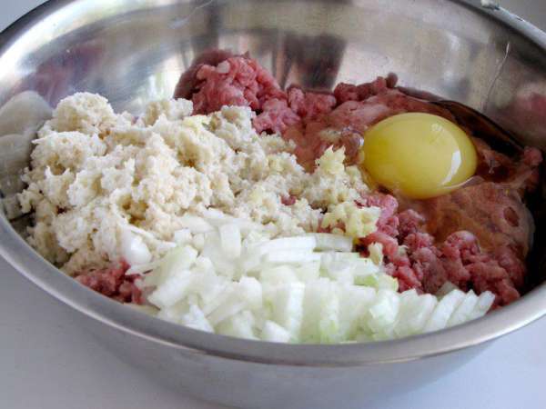 В мясной фарш добавить яйцо, мелко нарезанный лук и черствую белую булочку, размоченную в молоке (или вчерашний белый хлеб). Посолить, поперчить и хорошо перемешать.