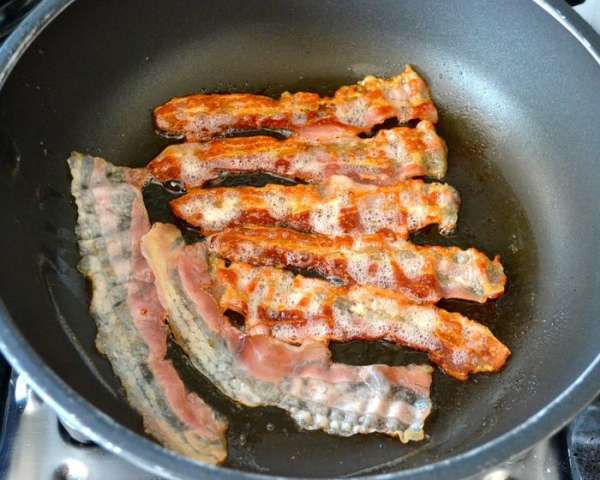 Тем временем в другой сковороде обжарить полосочки бекона. Выложить на салфетку.