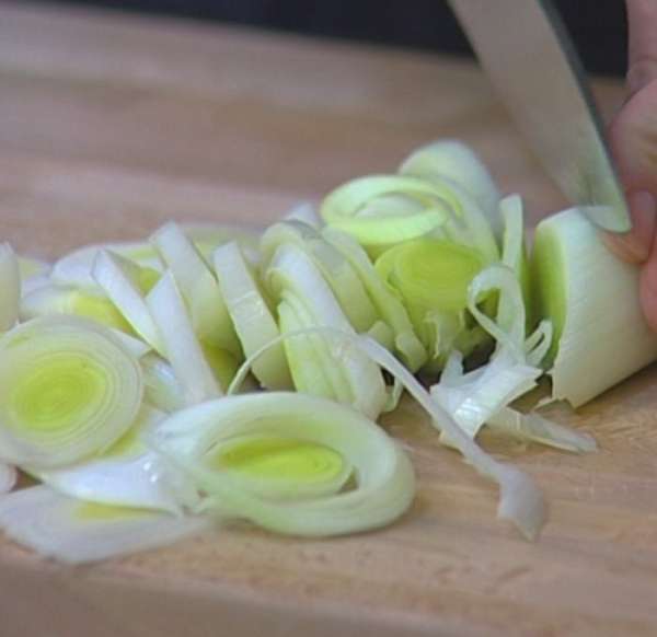 Светлую часть лука-порея нарезать наискосок тонкими кольцами. 
