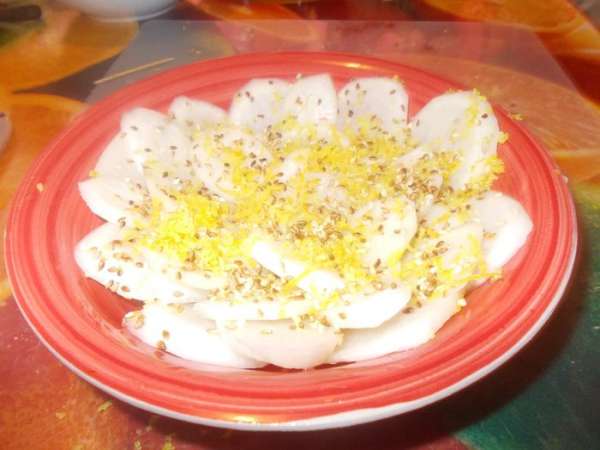 кунжутные семечки обжарить.рисовый уксус перемешать с сахаром,до растворения.дайкон очистить и нарезать колечками,уложить в глубокое блюдо слоями,полить заправкой посыпать щедро лимонной цедрой и присыпать семечками.убрать на 30 минут в холодильник.приятного аппетита.