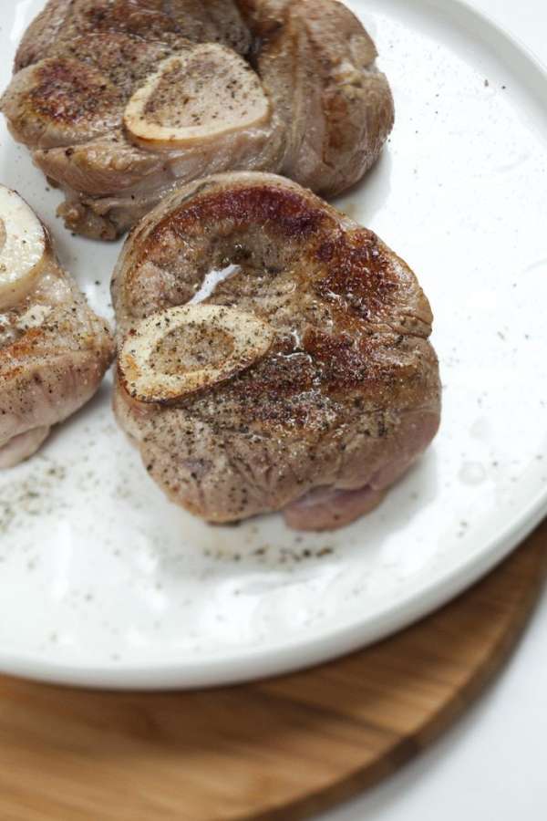 В тяжелой форме для запекания разогреть оливковое масло и обжарить мясо с обеих сторон до золотистого цвета. Выложить мясо на блюдо, посолить и поперчить его.