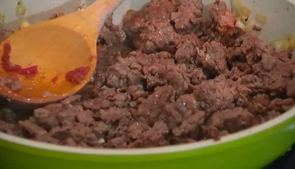 В сковороду с луком добавить мясной фарш и чеснок, слегка посолить, поперчить и перемешать. Обжаривать до готовности, разминая лопаткой комочки фарша.