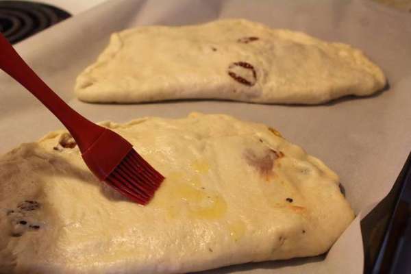На противень, застеленый пекарской бумагой, выложить фокаччи и смазать слегка маслом.