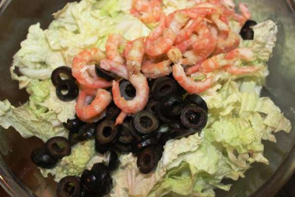 В салатнике перемешиваем капусту, маслины, куриные яйца и креветки. 

