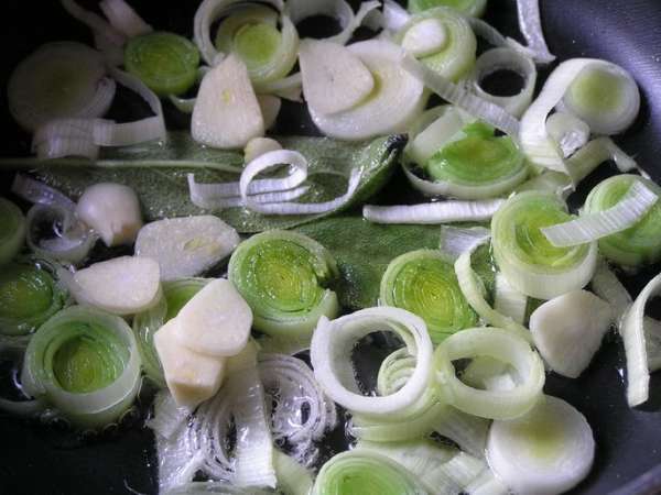 На растительном масле обжарить нарезанный кольцами лук-порей с чесноком и листьями шалфея.