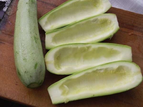 Кабачки разрезать вдоль, чтобы получилась лодочка. Удалить мягкую серединку, не задевая твердую часть. Посолить и сбрызнуть оливковым маслом. 