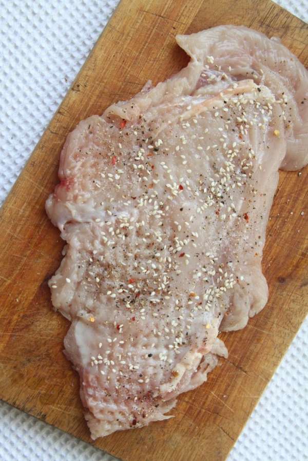 Котлету посолить и поперчить по вкусу и присыпать кунжутом с одной стороны (тоже самое проделываем со второй отбивной).
