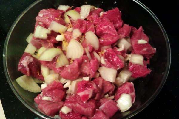 Нарезаем мясо порционными кусочками. Я люблю поменьше, где-то 2 на 2 см. Нарезаем крупно луковицу, мелко рубим чеснок, перемешиваем с мясом. К мясу также натираем цедру лимона, выдавливаем сок. Еще раз перемешиваем, накрываем крышкой и оставляем час мариноваться.