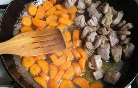 На растительном масле обжариваем кусочки мяса. Когда оно почти готово на вторую половину сковороды выкладываем крупно нарезанную морковь и жарим минут пять.