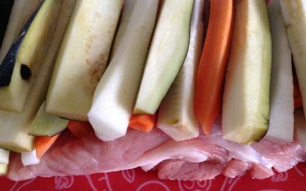 Разрезать мясо в виде рулета и уложить на мясо нарезанные овощи( баклажан нарезать и замочить на 20 минут в соленой воде, промыть и подсушить бумажной салфеткой). Посыпать приправами и солью.