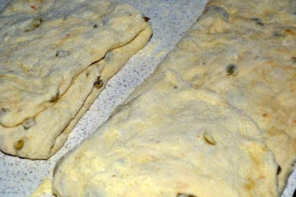 Затем щедро припорошить стол кукурузной мукой и выложить тесто. Сверху так же присыпать мукой. Ладошками расправить тесто в прямоугольный пласт. Разделить на 3-4 одинаковые полосы. Каждую сложить втрое. Одну треть завернуть к середине и запечатать,потом сложить к центру другую сторону и опять прижать ладонью.