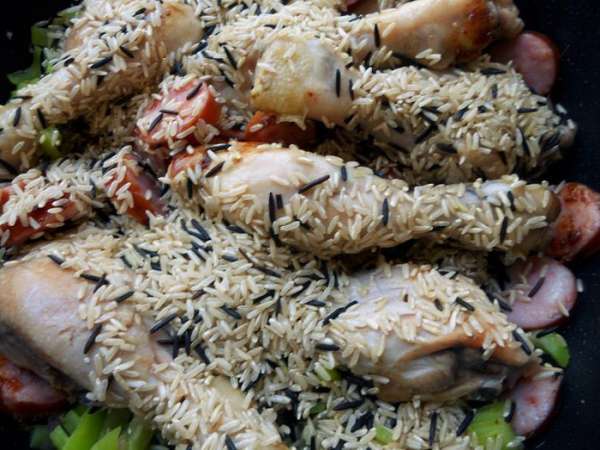 В сковороду вернуть курицу и колбаски, засыпать рис. В сковороду вернуть курицу и колбаски, засыпать рис.