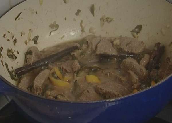 Добавить в кастрюлю с мясом закарамелизированный лимон, веточки мяты, корицу и лавровый лист. Тушить на медленном огне 40 минут.