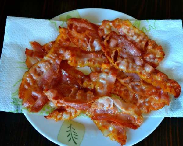 Нарезанный полосками бекон обжарить на сухой сковороде с двух сторон, чтобы он зажарился. Готовый бекон выложить на бумажное полотенце, чтобы убрать излишки жира.
