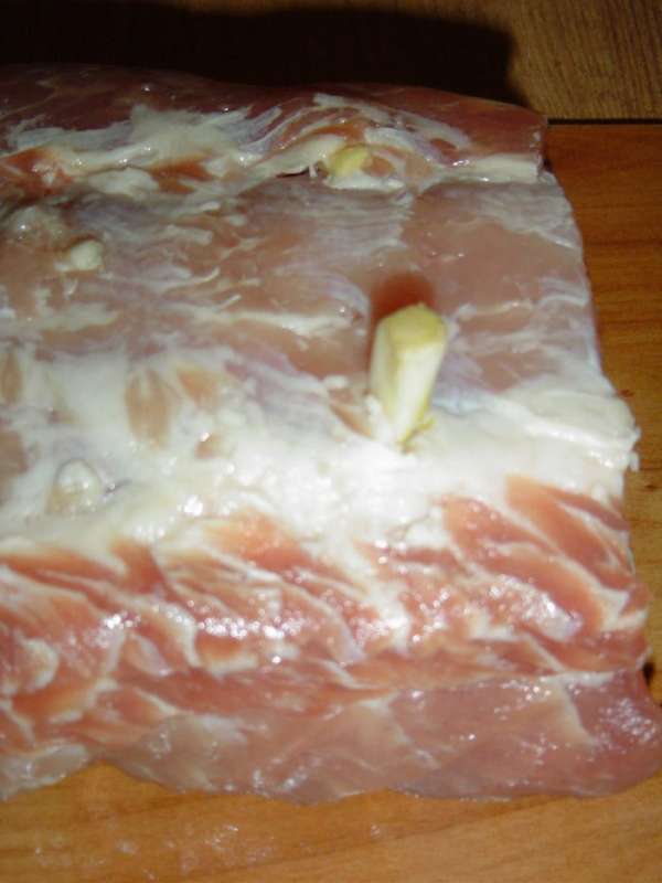 Делаем небольшие надрезы по всему периметру мяса и шпигуем чесноком. Делаем небольшие надрезы по всему периметру мяса и шпигуем чесноком.