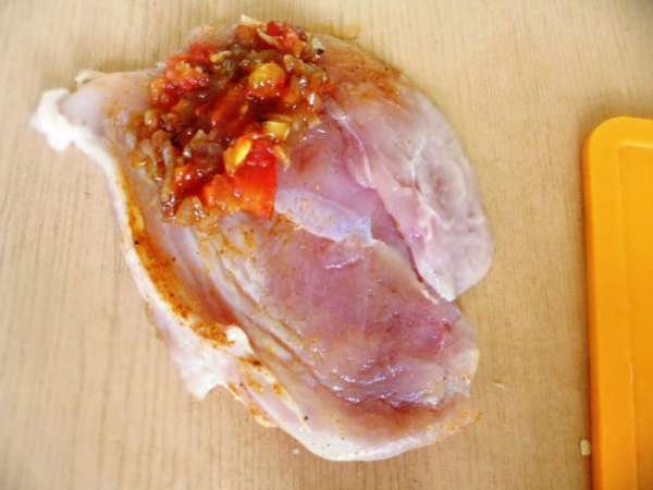 На край куриной грудки положить луково-помидорную смесь