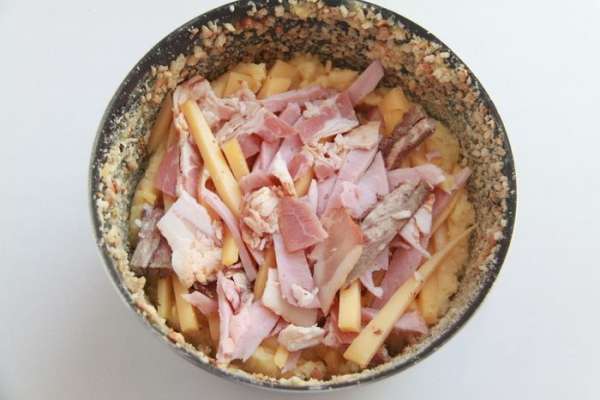 Выложить половину картофельного пюре, затем смесь сыра и мяса, придавить.