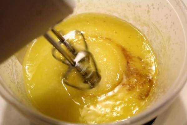 Включить духовку на 180°C. Тесто готовится быстро, поэтому к окончанию замеса, как раз будет готова и духовка. Растопленное сливочное масло смешать с сахаром до однородности, добавить в него ванильную эссенцию. По одному добавить яйца, каждый раз хорошо размешивая смесь.