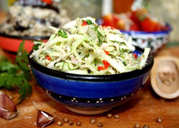 Капусту тонко нашинковать.Добавить  нарезанной зелени по вкусу(укроп,зелёный лук,кинза).Заправить ореховым соусом и сбрызнуть оливковым маслом.