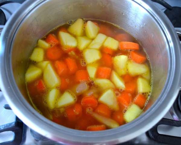 Залить все горячим (!) овощным бульоном, посолить по вкусу и варить на среднем огне 30 минут или до готовности моркови.