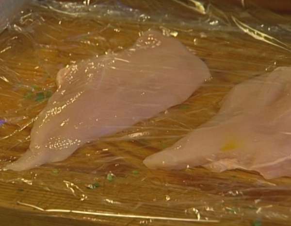 Поместить куриные грудки между двумя слоями пищевой пленки и отбить скалкой. Пленку убрать, а грудки поперчить и посолить.